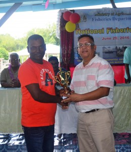 Head of the Ministry of Agriculture's Fisheries Dept. Mr Denzil Roberts handing over a trophy to one of the participants in the Fisherfolk Day celebrations