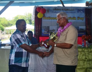 Minister Holder handing over a trophy to the olders serving fisherman persent at the Fisherfolk day celebrations