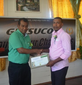 GuySuCo representative handing over award to Honour Roll Awardees