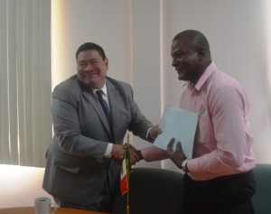 Mexico's Ambassador to Guyana, H.E Ivan Roberto Sierra recieves rice documents from GRDB official