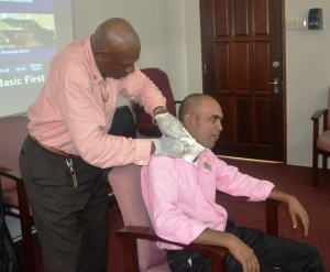 MOA staff demonstrating how to bandage a person with a neck injury during the Ministry's CPR and First Aid work shop
