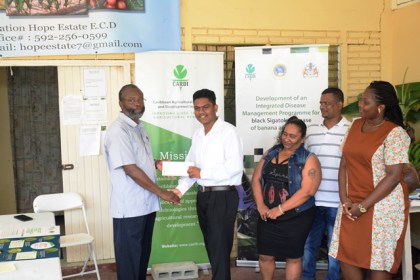 CARDI Country Representative, Dr. Cyril Roberts handing over a reward to Eion Jotis in the presence of his parents and his teacher.
