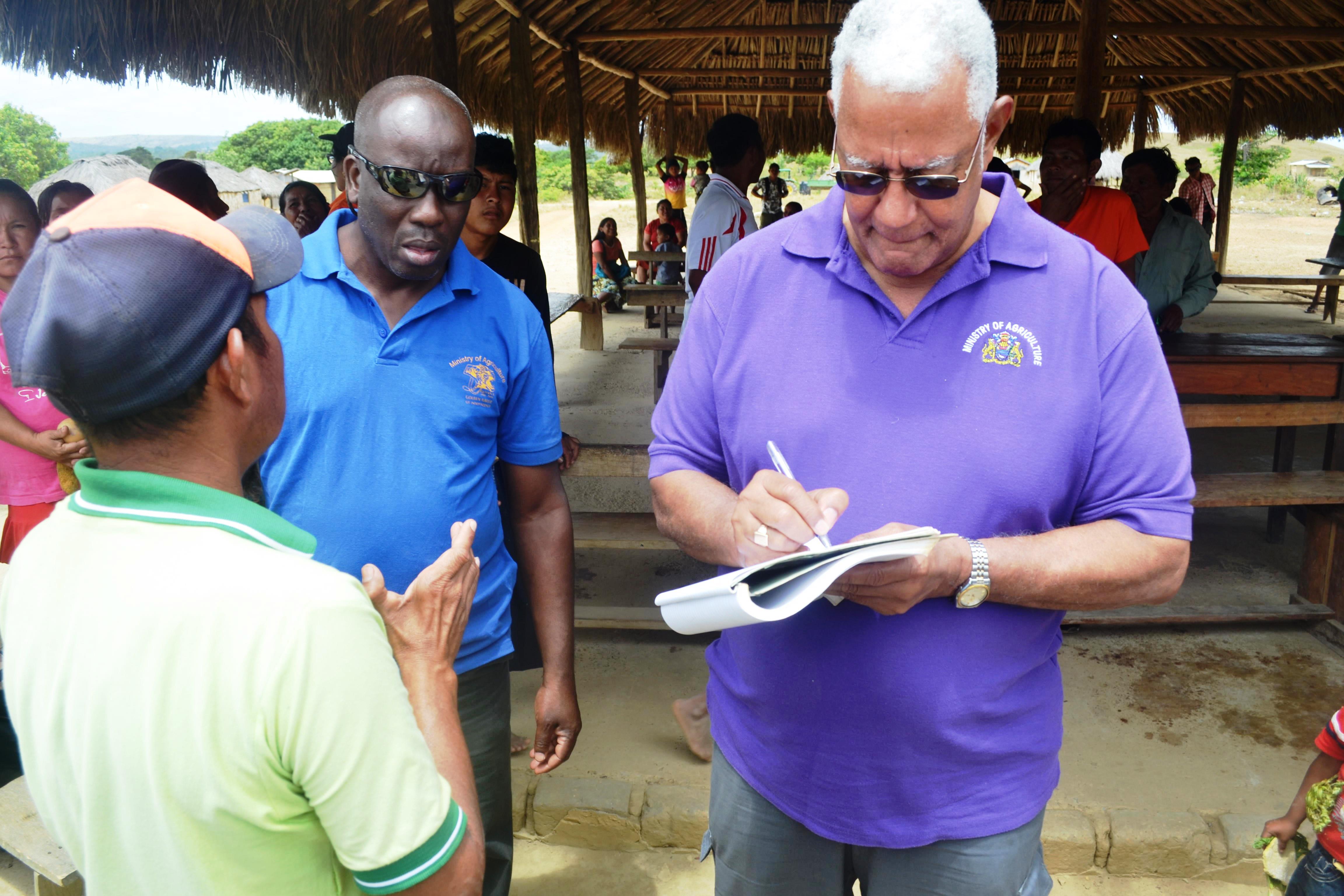 Minister Holder while collecting a report from the village toshao