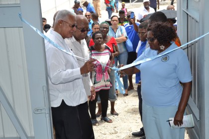 Minister Holder assists in the cutting of the ribbon to officially commission the pump station.