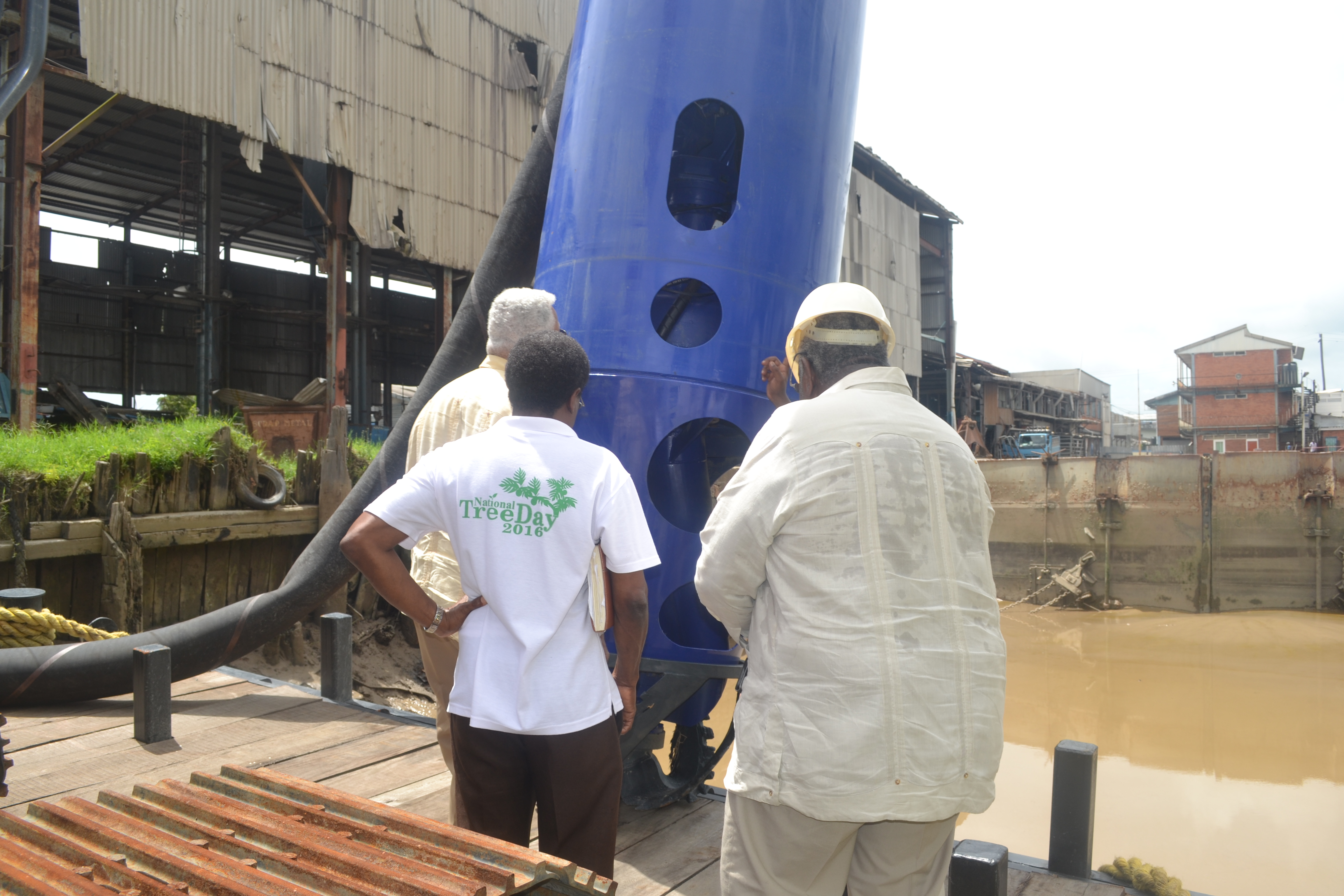 Minister Holder and other officials while taking a closer look at the dredge pump
