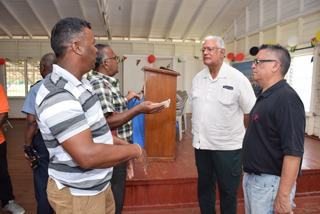 Agriculture Minister, Noel Holder and Chief Fisheries Officer, Denzil Roberts being engaged by fishermen.